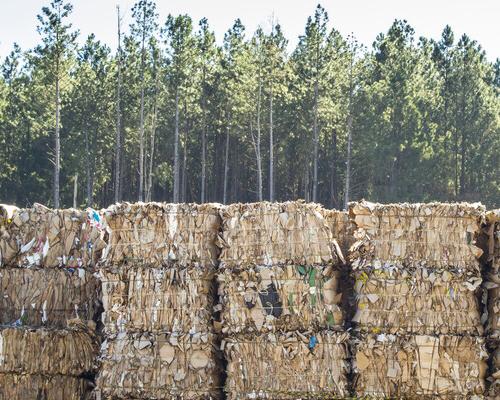 Stacks of paper bales with trees in the background